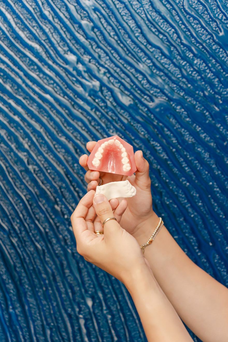 A clear aligner and a dental model held up at Downtown Orthodontics